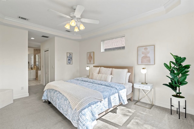 bedroom featuring ornamental molding, light colored carpet, ensuite bath, and a tray ceiling