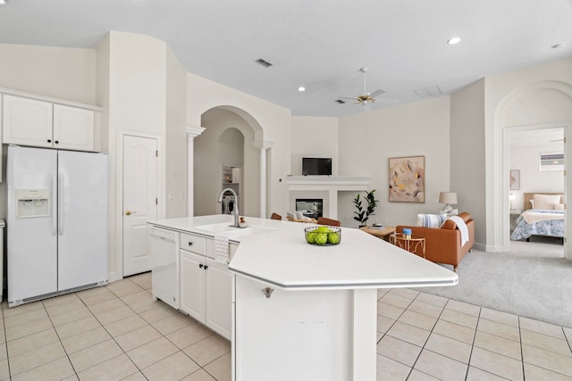 kitchen featuring sink, white appliances, white cabinets, and a center island with sink