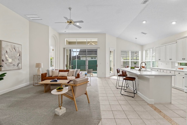 living room with ceiling fan, sink, a textured ceiling, and light tile patterned floors