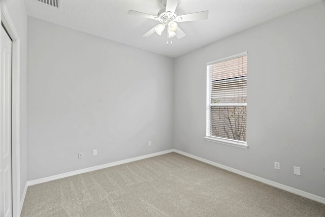 unfurnished room featuring light colored carpet, a textured ceiling, and ceiling fan