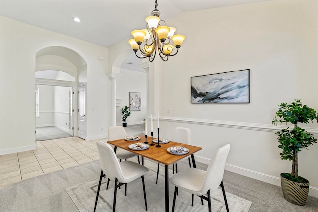 tiled dining space featuring vaulted ceiling, decorative columns, and a chandelier