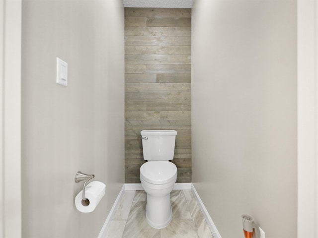 bathroom with wooden walls and toilet