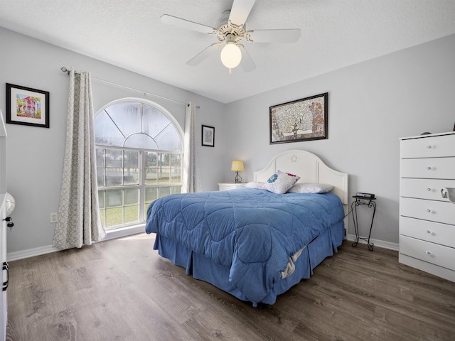 bedroom with a textured ceiling, ceiling fan, and dark hardwood / wood-style floors