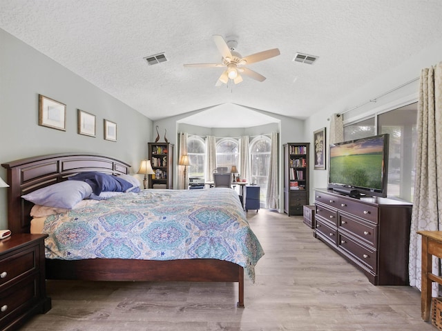 bedroom with a textured ceiling, ceiling fan, lofted ceiling, and light wood-type flooring