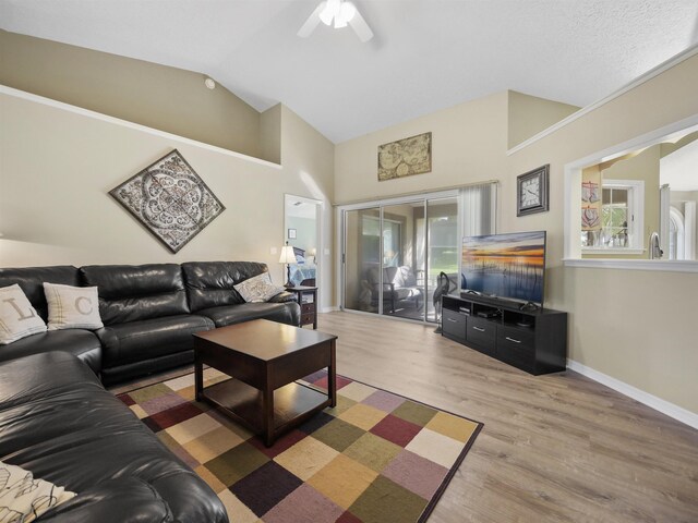 living room with ceiling fan, plenty of natural light, lofted ceiling, and hardwood / wood-style flooring