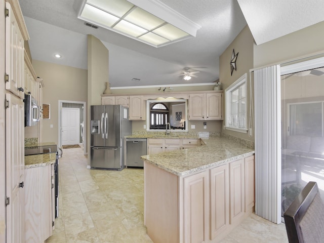 kitchen featuring kitchen peninsula, appliances with stainless steel finishes, light stone countertops, sink, and high vaulted ceiling