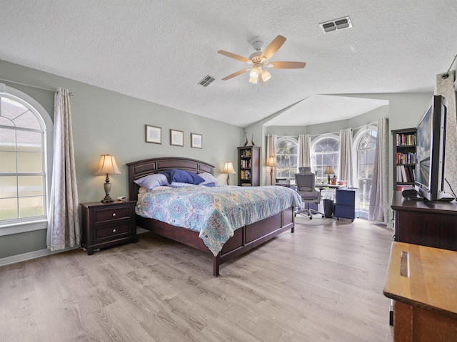 bedroom with ceiling fan, lofted ceiling, a textured ceiling, and light hardwood / wood-style flooring