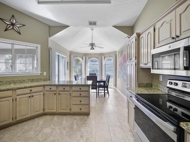 kitchen featuring light stone countertops, ceiling fan, stainless steel appliances, and a textured ceiling