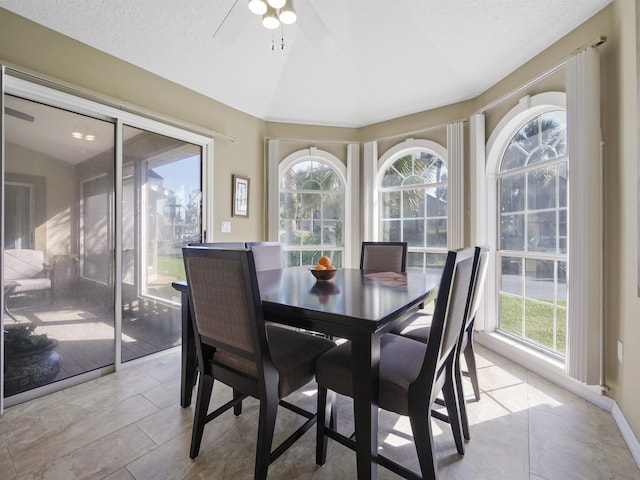 dining area with a textured ceiling, a wealth of natural light, ceiling fan, and vaulted ceiling