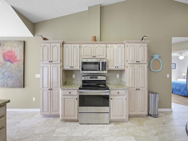 kitchen with appliances with stainless steel finishes, a textured ceiling, and vaulted ceiling