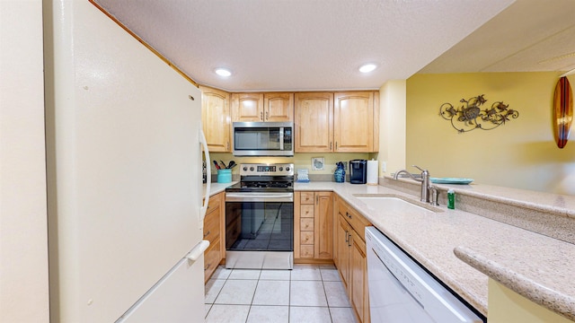 kitchen featuring a textured ceiling, stainless steel appliances, sink, light brown cabinets, and light tile patterned flooring