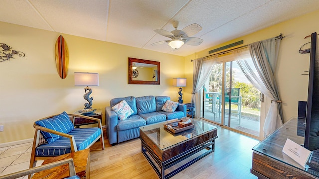 living room with ceiling fan, light hardwood / wood-style floors, and a textured ceiling