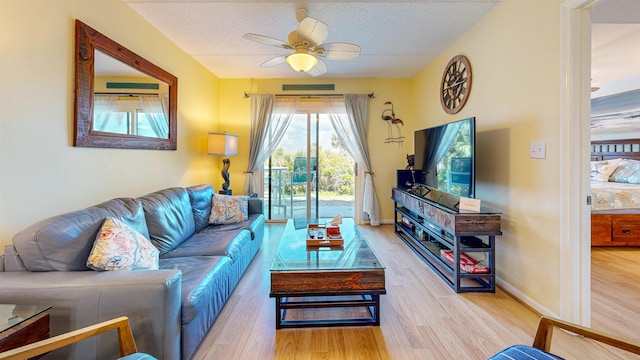 living room featuring ceiling fan, light hardwood / wood-style floors, and a textured ceiling