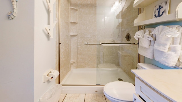 bathroom featuring tile patterned flooring, vanity, a shower with shower door, and toilet