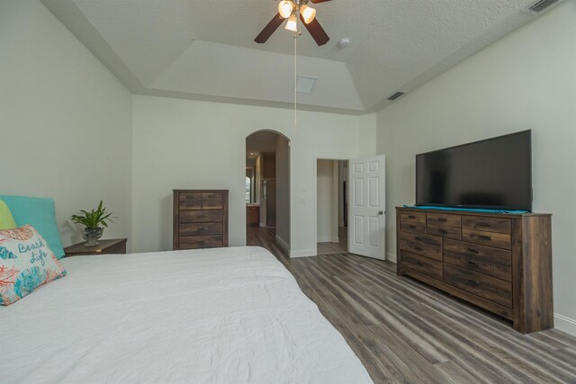 bedroom with a high ceiling, hardwood / wood-style flooring, ceiling fan, a textured ceiling, and a tray ceiling