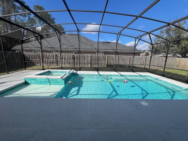 view of swimming pool featuring glass enclosure and an in ground hot tub