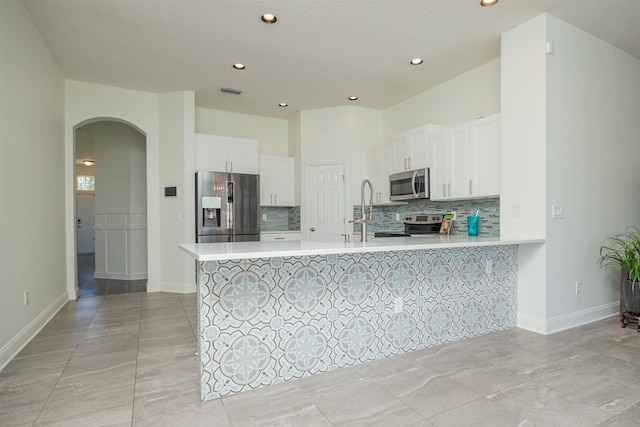 kitchen featuring kitchen peninsula, sink, a textured ceiling, appliances with stainless steel finishes, and white cabinetry