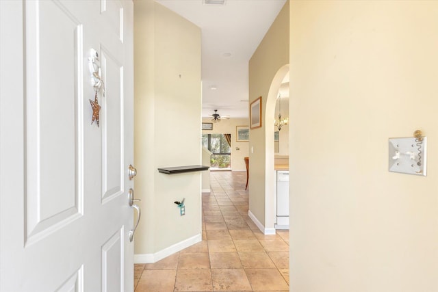 hallway with visible vents, light tile patterned flooring, baseboards, and arched walkways