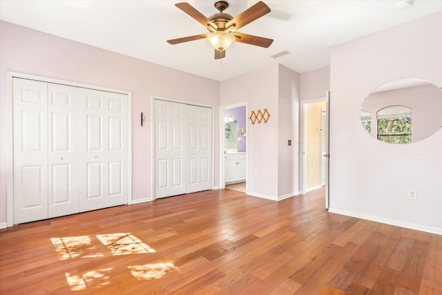 unfurnished bedroom featuring visible vents, two closets, baseboards, ceiling fan, and light wood-style flooring