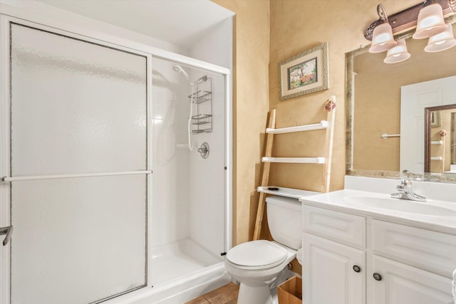 bathroom featuring a stall shower, toilet, and vanity