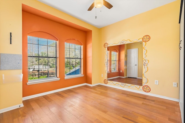 empty room featuring baseboards, wood finished floors, and a ceiling fan