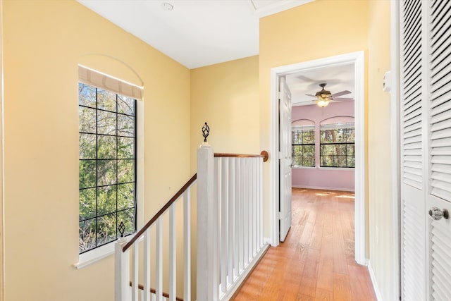 hallway featuring an upstairs landing, light wood-type flooring, and baseboards