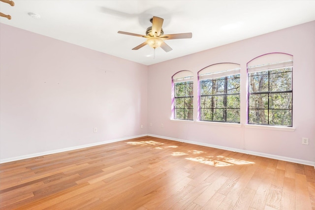 spare room featuring baseboards, light wood-type flooring, and a ceiling fan