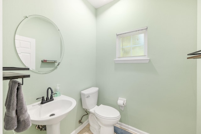 half bathroom with a sink, toilet, and baseboards