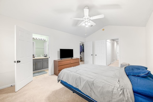 bedroom featuring lofted ceiling, connected bathroom, light carpet, a ceiling fan, and a closet