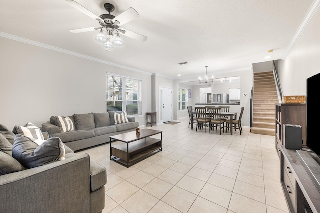 living room featuring light tile patterned floors, visible vents, stairway, ornamental molding, and ceiling fan with notable chandelier