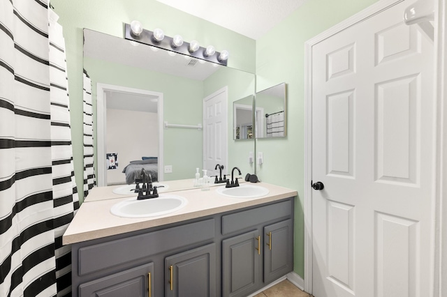 ensuite bathroom featuring double vanity, ensuite bath, and a sink