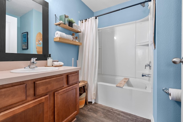 bathroom with vanity, shower / tub combo with curtain, a textured wall, and wood finished floors