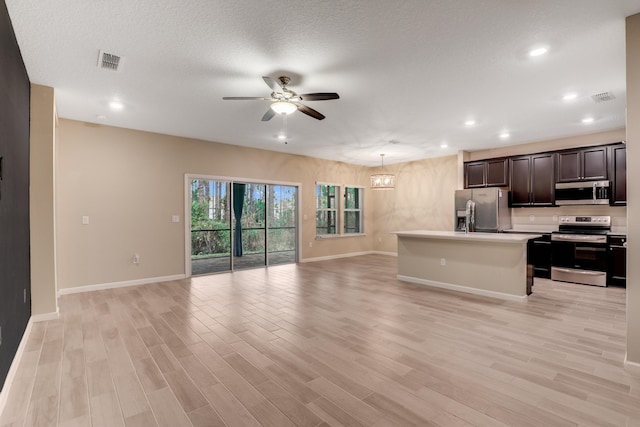 kitchen with a center island with sink, stainless steel appliances, ceiling fan with notable chandelier, and light hardwood / wood-style floors