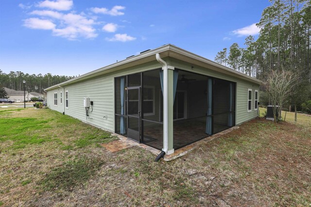 view of side of property featuring a yard, central AC unit, and a sunroom