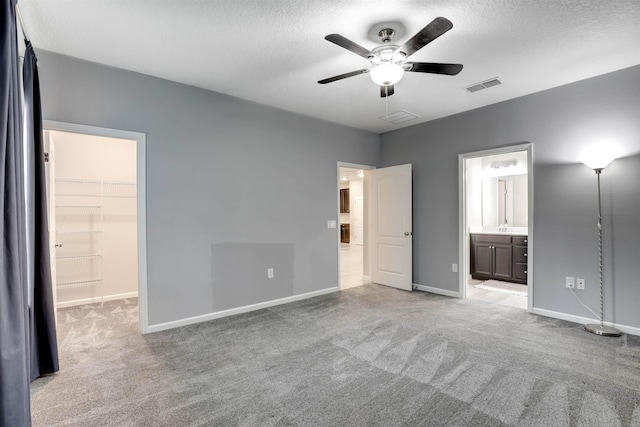 unfurnished bedroom with ceiling fan, light colored carpet, a walk in closet, and a closet