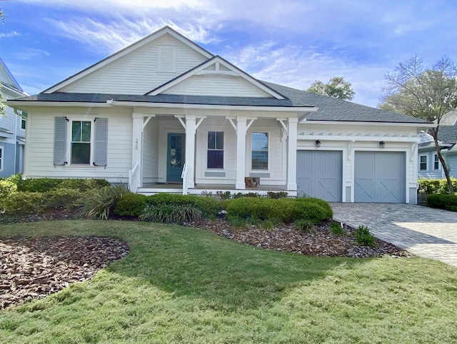 view of front of property featuring covered porch, a front yard, and a garage