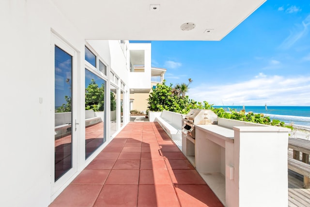 view of patio featuring a beach view, a water view, and a grill