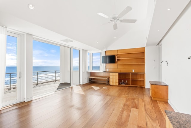 unfurnished living room featuring ceiling fan, light hardwood / wood-style flooring, a healthy amount of sunlight, and a view of the beach