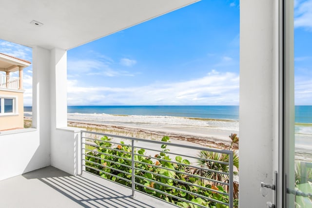 balcony with a water view and a view of the beach