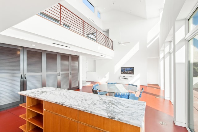 kitchen featuring a high ceiling, light stone counters, and ceiling fan