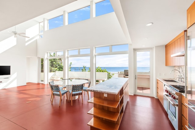 kitchen featuring ceiling fan, a center island, sink, stainless steel appliances, and a water view