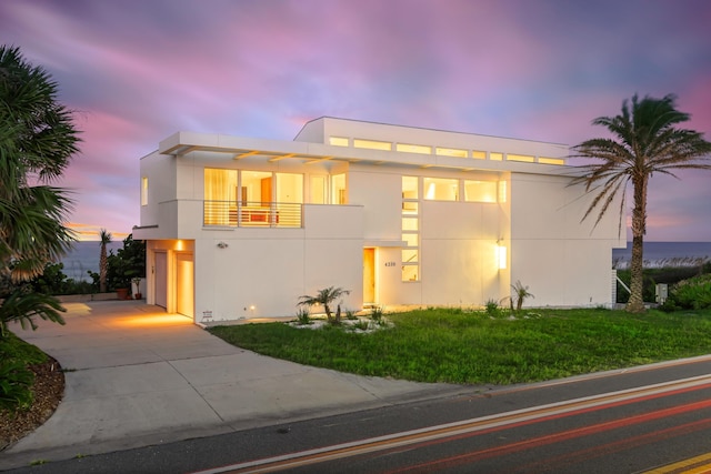 modern home with a lawn, a garage, and a balcony