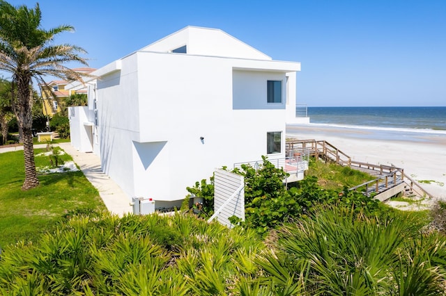 view of property exterior with a water view and a view of the beach