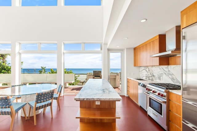 kitchen featuring sink, wall chimney exhaust hood, a kitchen island, high quality appliances, and a water view