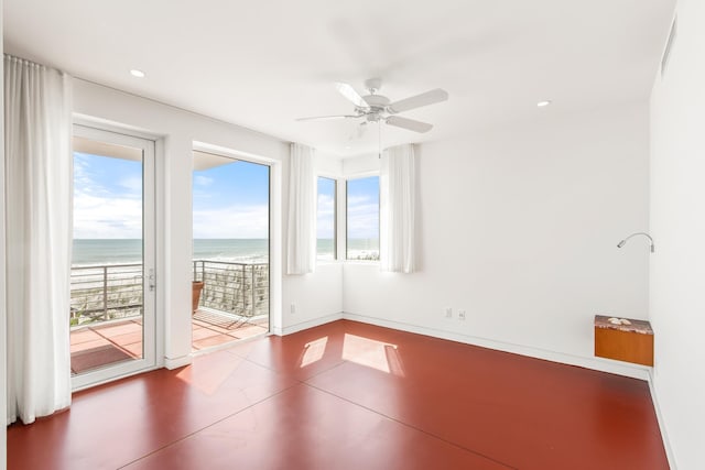 spare room with plenty of natural light, ceiling fan, a water view, and a view of the beach