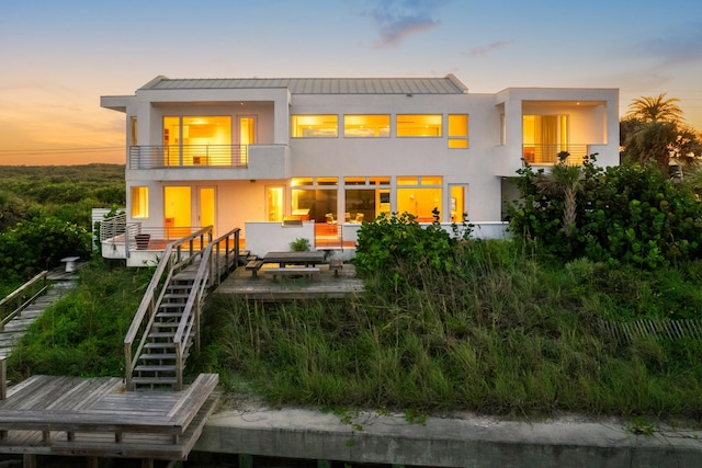 back house at dusk featuring a balcony