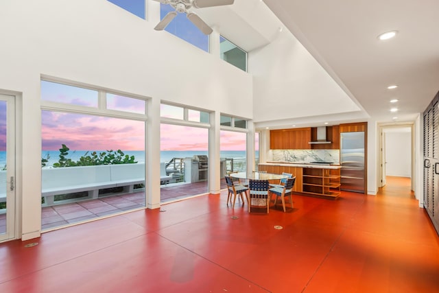 interior space featuring ceiling fan, a water view, and a high ceiling