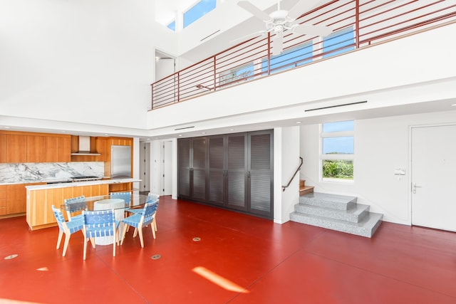 dining area with ceiling fan and a towering ceiling