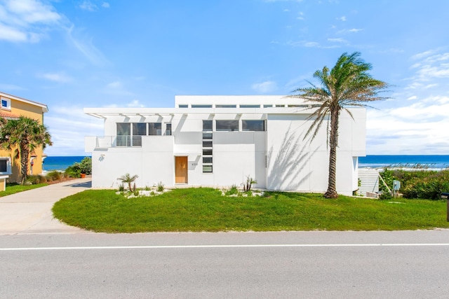 view of front facade with a balcony, a water view, and a front yard