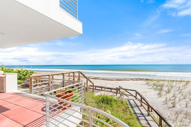 balcony with a water view and a view of the beach